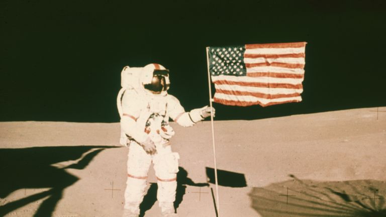 Alan Shepard holds the pole of a US flag on the surface of the moon during the Apollo 14 mission.