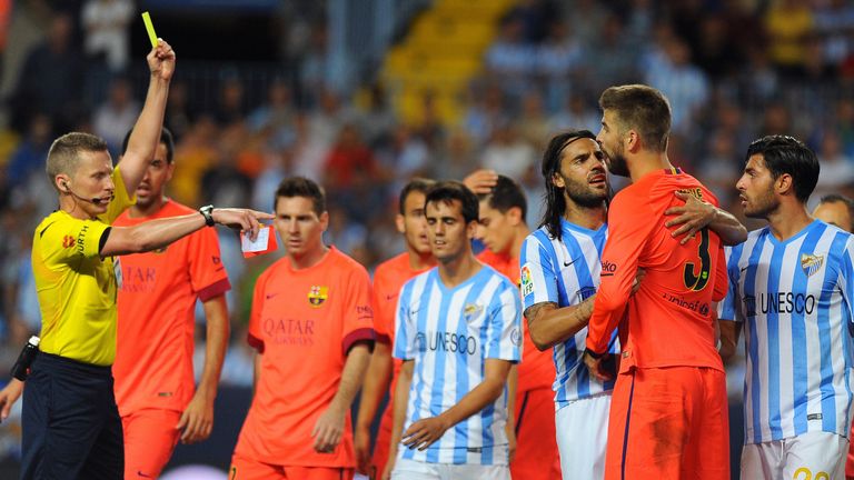 The referee shows a yellow card to Barcelona's defender Gerard Pique (2ndR) during the Spanish league football 