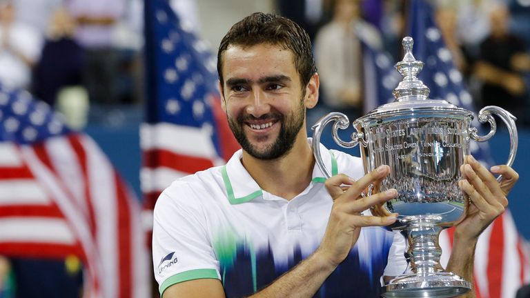 Marin Cilic, of Croatia, holds up the championship trophy after defeating Kei Nishikori, of Japan, in the championship match of the US Open
