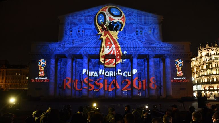 People watch as the facade of the historical Bolshoi Theatre is illuminated with the official emblem of the 2018 FIFA World Cup to be held in Russia