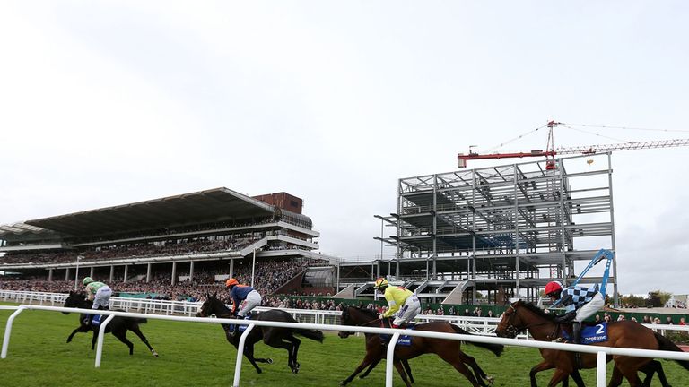 Runners pass the building work on the new grandstands during the Neptune Investment Management Novices' Hurdle at Cheltenham Racecourse.