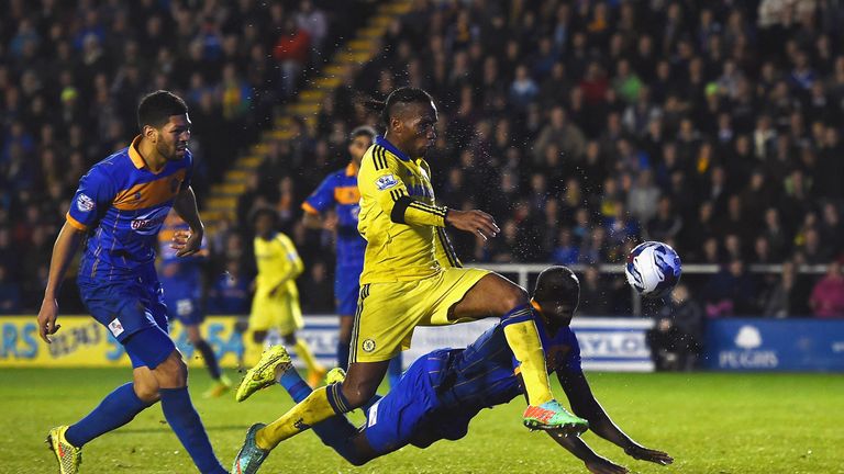 Jermaine Grandison of Shrewsbury Town heads the ball clear of Didier Drogba of Chelsea to score an own goal