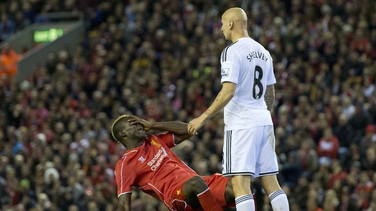 Liverpool's Italian forward Mario Balotelli (L) reacts holding his face after a confrontation with Swansea City's English midfielder Jonjo Shelvey