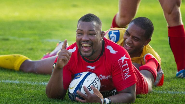 Toulon's flanker Steffon Armitage celebrates after scoring a try despite a tackle by Scarlets' wing Michael Tagicakibau 