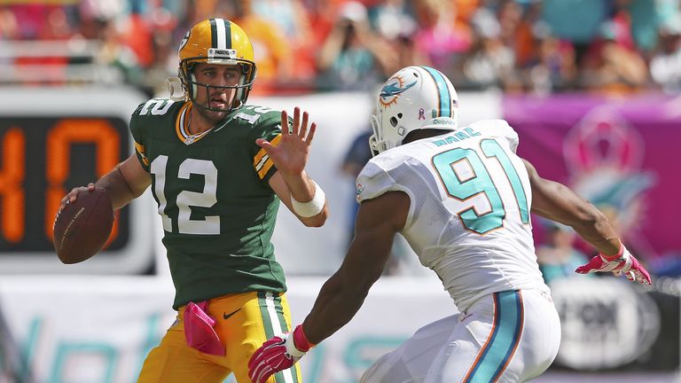 MIAMI GARDENS, FL - OCTOBER 12:  Quarterback Aaron Rodgers #12 of the Green Bay Packers tries to  hold off defender defensive end Cameron Wake #91 of the M