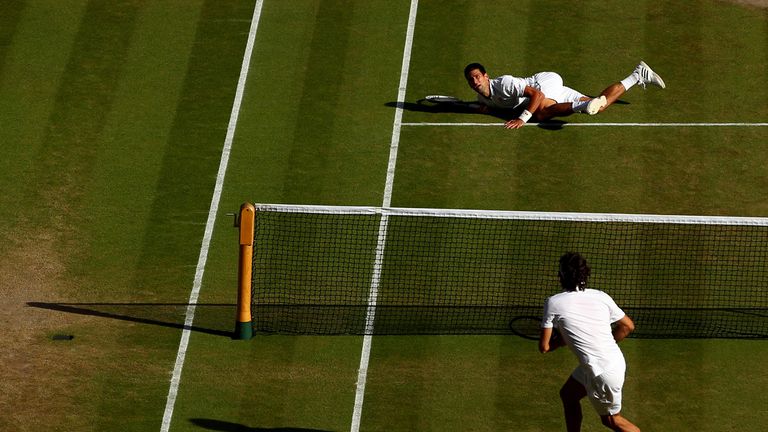 LONDON, ENGLAND - JULY 06:  Novak Djokovic of Serbia dives to make a return as Roger Federer of Switzerland stands at the net during the Gentlemen's Single