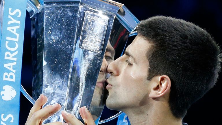 Novak Djokovic holds the men's singles trophy following Roger Federer's withdrawal during the Barclays ATP World Tour Finals at The O2 Arena, London.