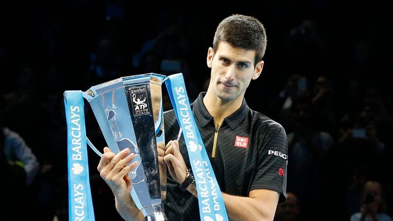 Novak Djokovic (left) holds the men's singles trophy while being applauded by Chris Kermode, the ATP's executive chairman, following Roger Federer's withdr