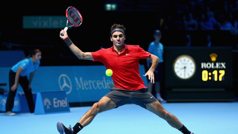 Roger Federer of Switzerland stretches to play a forehand against Milos Raonic