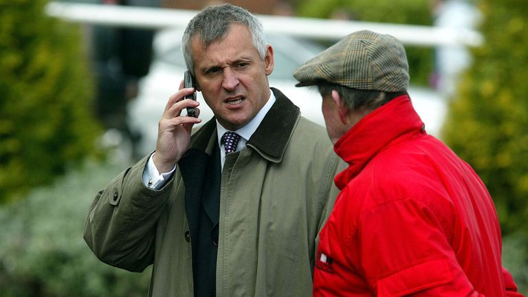 Ex jockey Graham Bradley on his mobile phone is stopped by a steward at the Cheltenham Festival.