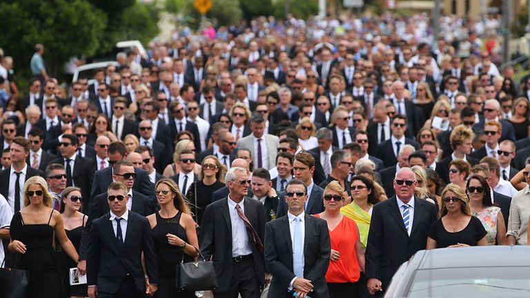 Mourners walk behind the hearse as it departs the Funeral Service for Phillip Hughes
