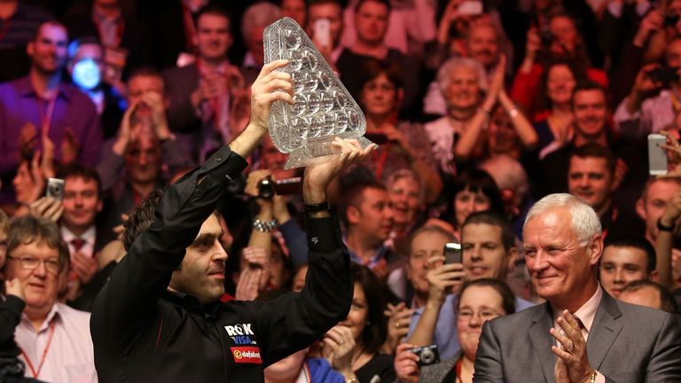 Ronnie O'Sullivan celebrates with the trophy watched over by World Snooker Chairman Barry Hearn, (right) following his victory over Mark Selby during the 2