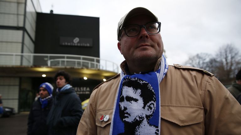 A Chelsea fan wears a scarf showing the face of Chelsea's former English midfielder Frank Lampard who now plays for Manchester City outside the ground