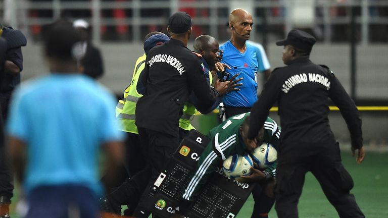 Security guards escort referee Rajindraparsad Seechurn at the end of the  match