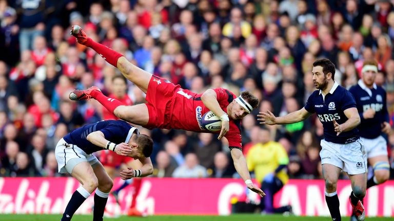 Dan Biggar of Wales is taken out in the air by Finn Russell of Scotland