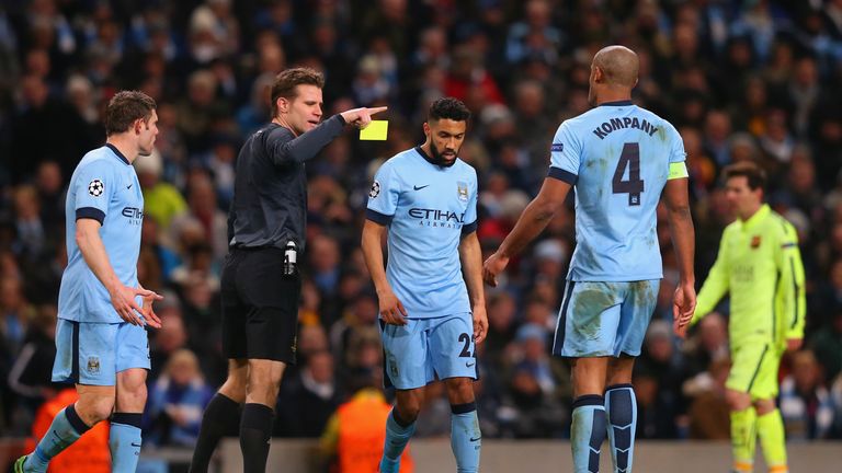 Referee Dr. Felix Brych shows Gael Clichy of Manchester City a yellow card during the UEFA Champions League Round of 16 v Barcelona
