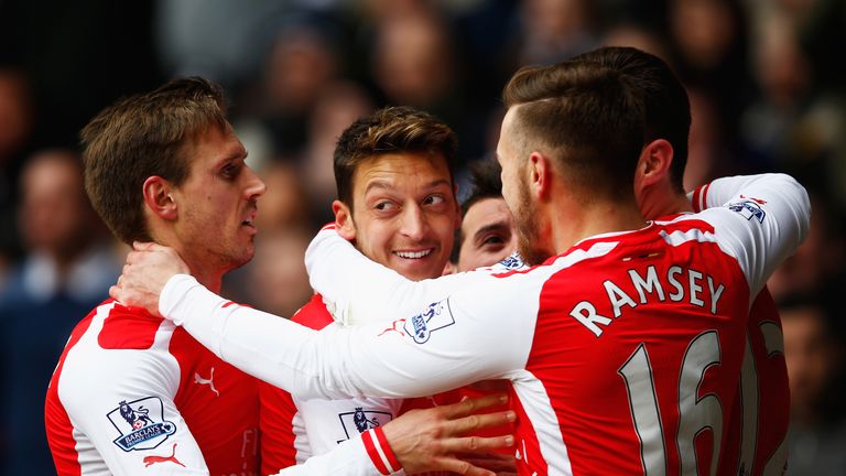 Mesut Ozil of Arsenal celebrates scoring the opening goal with team mates during the Barclays Premier League match at Tottenham