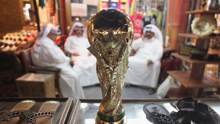 Arab men sit at a shoemaker's stall with a replica of the FIFA World Cup trophy in the Souq Waqif traditional market on October 