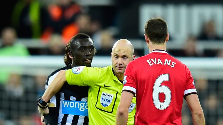 Referee Anthony Taylor steps in as Manchester United player Jonny Evans (c) and Papiss Cisse of Newcastle have words