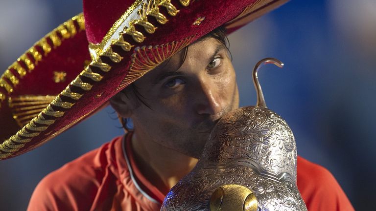 Spanish tennis player David Ferrer wears a traditional Mexican mariachi hat while holding the winning trophy 