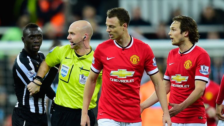 Referee Anthony Taylor steps in as Manchester United player Jonny Evans (c) and Papiss Cisse of Newcastle argue