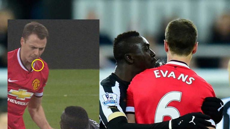 Manchester United player Jonny Evans looks on as Papiss Cisse of Newcastle appears to spit