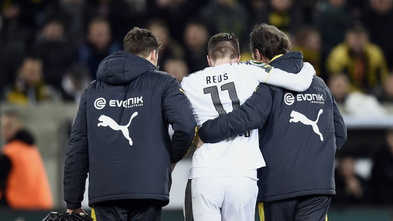 Dortmund's striker Marco Reus (C) is helped by staff as he leaves the pitch after being wounded during the German 