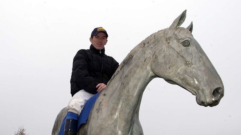 15 Nov 2000: Champion jockey Tony McCoy sits astride a statue of Desert Orchid