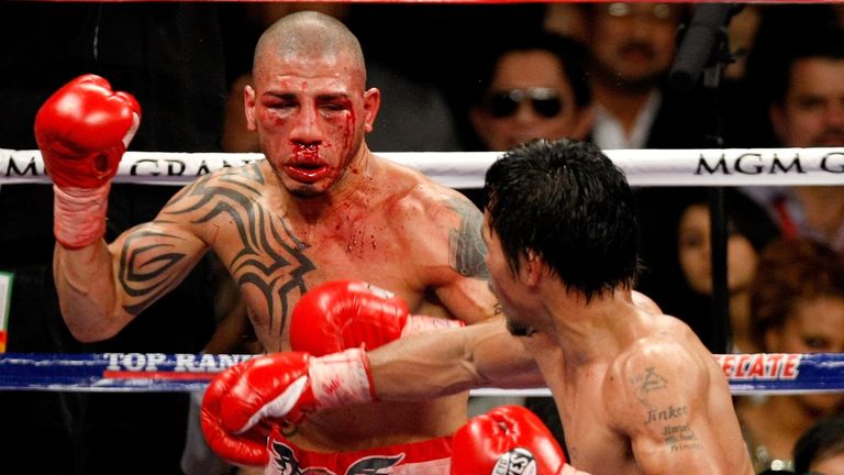 A bloodied Miguel Cotto is backed up by Manny Pacquiao in their WBO welterweight title clash in 2009