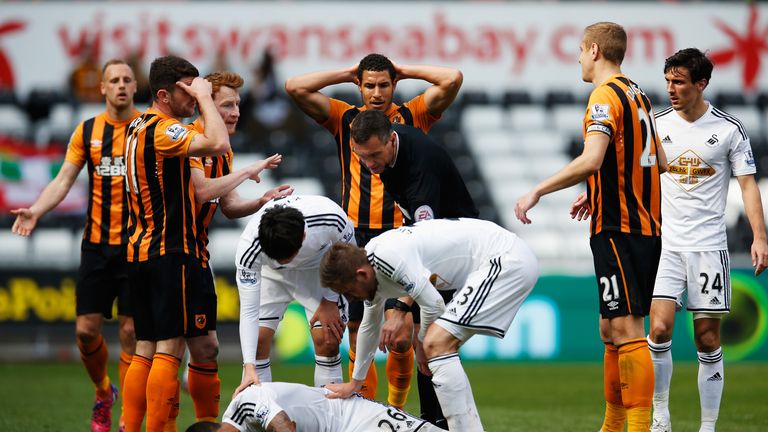 Referee Andre Marriner checks on Swansea's Kyle Naughton after showing the red card to Hull's David Meyler
