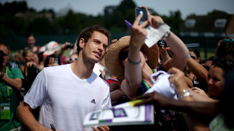 Andy Murray of Great Britain poses for photographs with fans after a practice session on day twelve of Wimbledon 