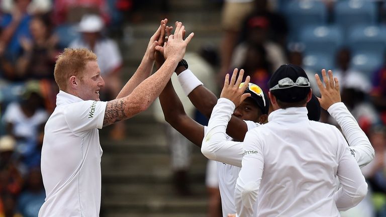 England's cricketer Ben Stokes (L) celebrates with teammates after dismissing West Indies batsman Shiv Chanderpaul during the second Test