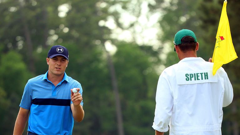 Jordan Spieth of the United States makes birdie on the 14th green as his caddie Michael Greller looks on during the first round of the Masters