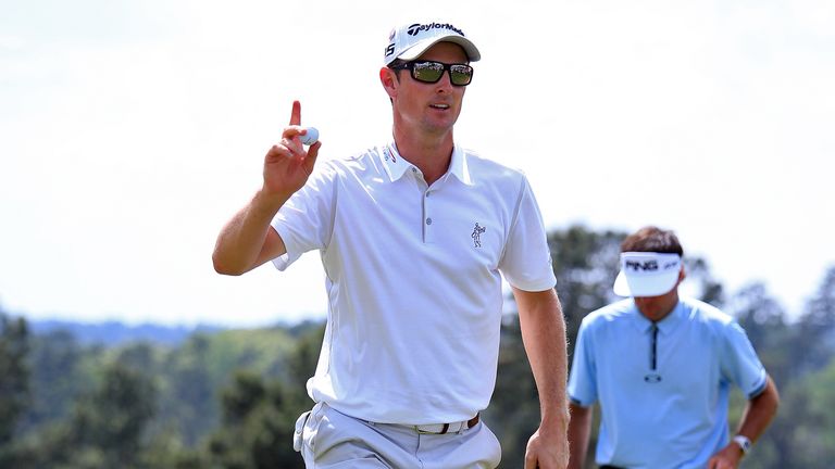 Justin Rose of England waves to the gallery on the 18th green after a five-under par 67 as  Bubba Watson of the United States look