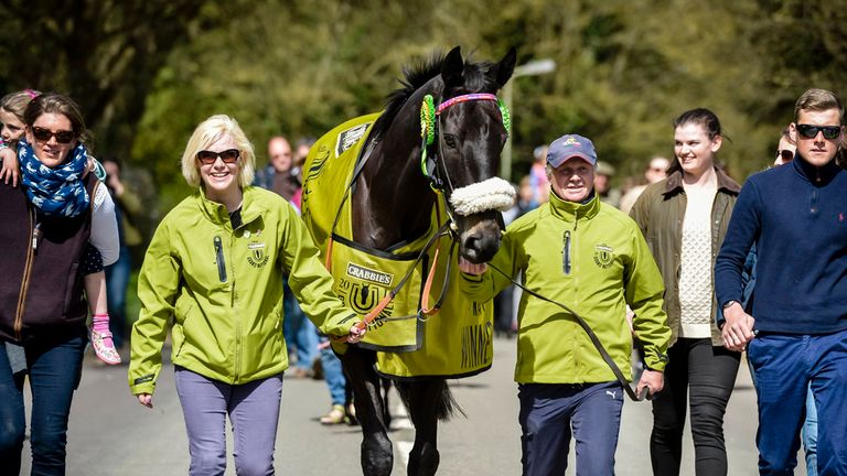 Many Clouds is followed by locals and well-wishers in celebration after winning the Crabbies Grand National, during a parade in Lambourn