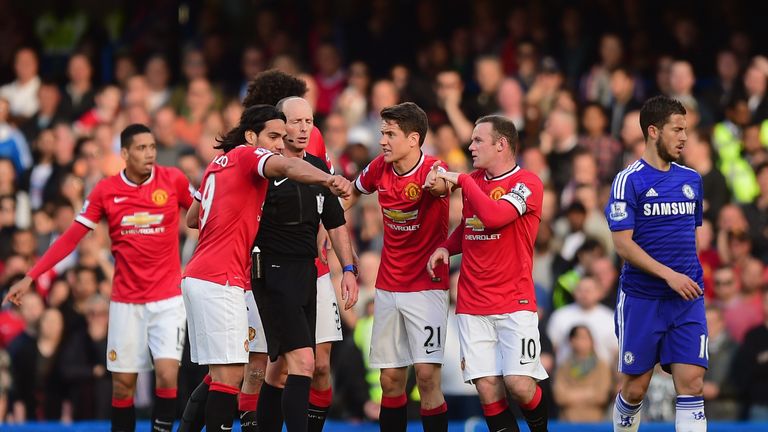 Referee Mike Dean is surrounded by Manchester United players