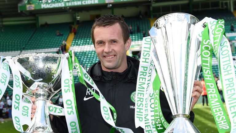 Celtic manager Ronny Deila celebrates with the Scottish League Cup and the Scottish Premiership trophy