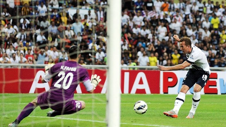 Tottenham Hotspur striker Harry Kane (R) takes a shot at goal past Malaysia All Stars goalkeeper Khairul Fahmi (L) during a friendly match