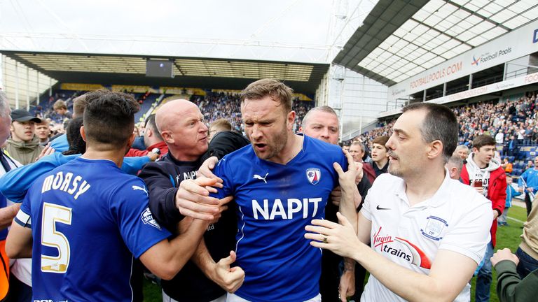 Chesterfield's Ian Evatt is restrained after he reacts to the alleged incident during the pitch invasion at Deepdale