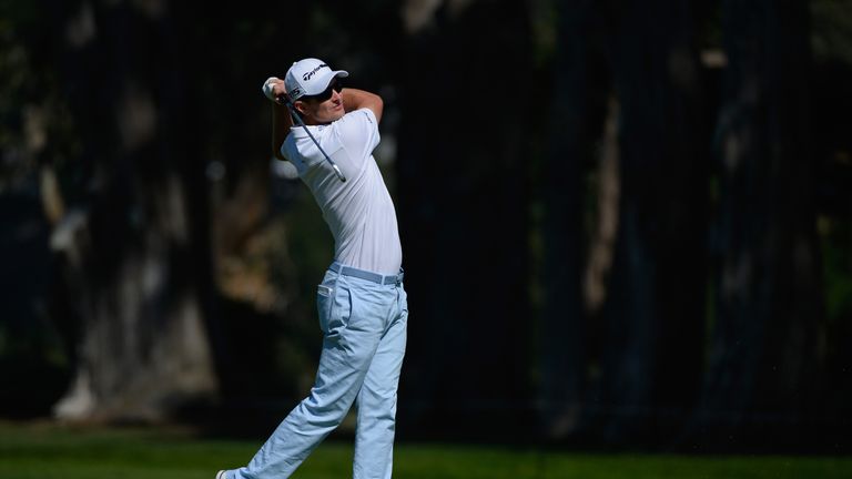 Justin Rose of England hits from the fairway on the first hole