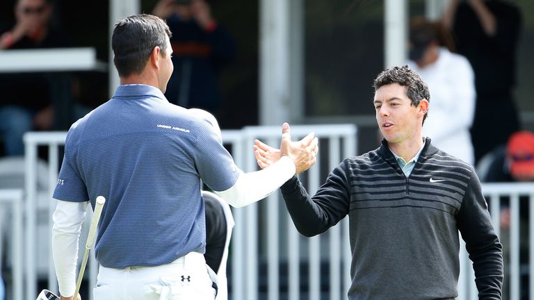 Rory McIlroy of Northern Ireland shakes hands with Gary Woodland on the 16th hole green after winning their championship match