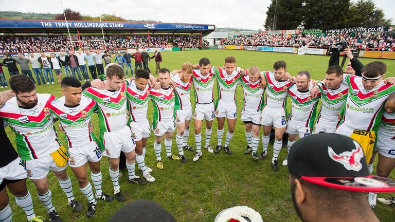 Keighley Cougars form a circle around Danny Jones's wreath on the field.