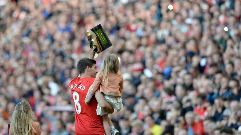 Steven Gerrard holding his daughter Lourdes waves a 'Golden Samba' presented to him by a young fan in the crowd as he says farewell