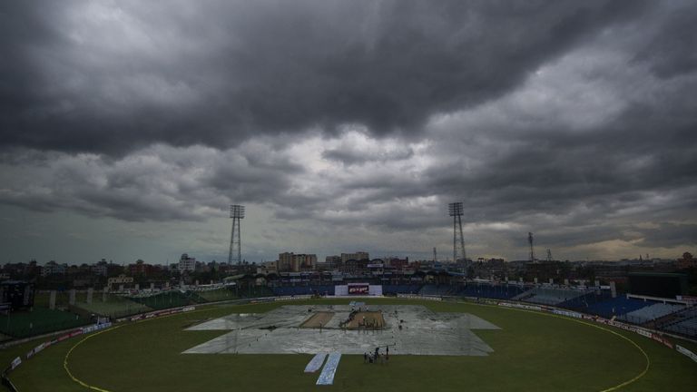 Bangladeshi ground staff cover the playing field as rain comes during the second day of the only cricket Test match between Bangladesh and India