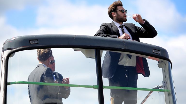 Spectator enjoys a drink on an open top bus