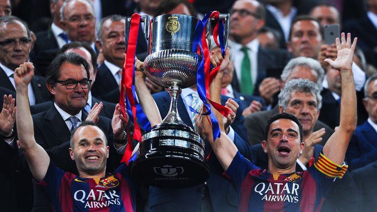 FC Barcelona players Andres Iniesta (L) and Xavi Hernandez of FC Barcelona celebrate with the trophy after winning the Copa del