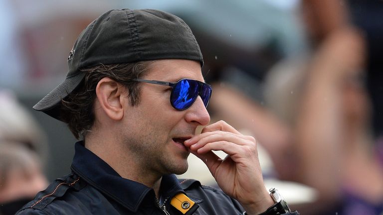 Bradley Cooper stands as a rain shower temporarily halts play in the men's quarter-finals match between Roger Federer and Gilles Simon 