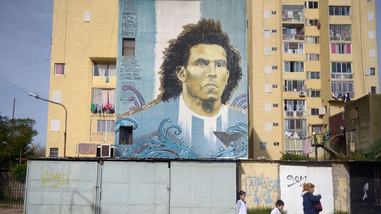 A familly passes by a wall painted with a portrait of Carlos Tevez in Fuerte Apache on the outskirts of Buenos Aires, Argentina, on June 04, 2015