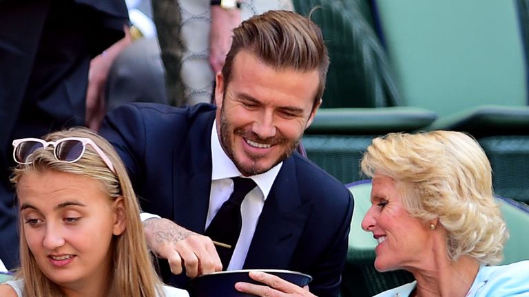 Gill Brook offers a sweet to David Beckham in the royal box during day 10 of Wimbledon