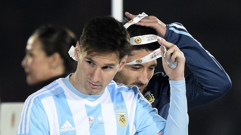 Argentina forward Lionel Messi (L) and defender Milton Casco take off second place medals of 2015 Copa America final in Santiago, Chile